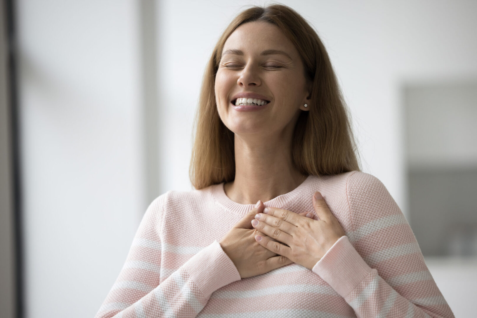 lady with eyes closed and hands across heart looking happy